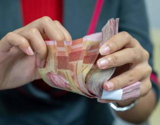 A foreign exchange officer counts rupiah banknotes for customers in Jakarta on March 12, 2020. - The rupiah weakened against the dollar as affected by the slowing economy due to the Covid-19 Corona virus issue. (Photo by BAY ISMOYO / AFP) (Photo by BAY IS