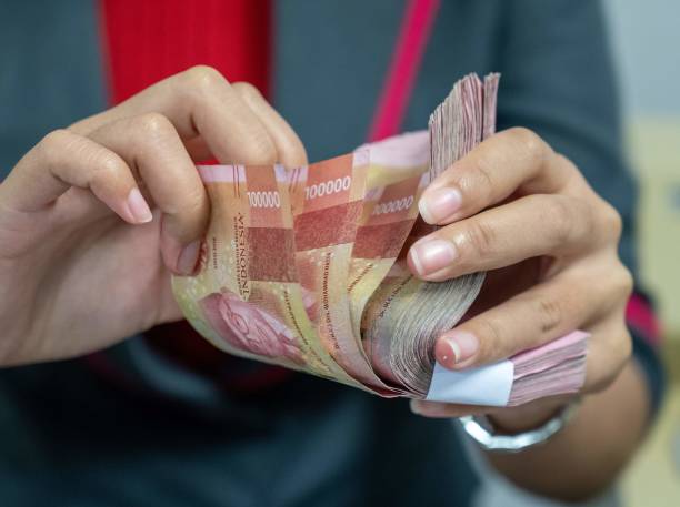 A foreign exchange officer counts rupiah banknotes for customers in Jakarta on March 12, 2020. - The rupiah weakened against the dollar as affected by the slowing economy due to the Covid-19 Corona virus issue. (Photo by BAY ISMOYO / AFP) (Photo by BAY IS