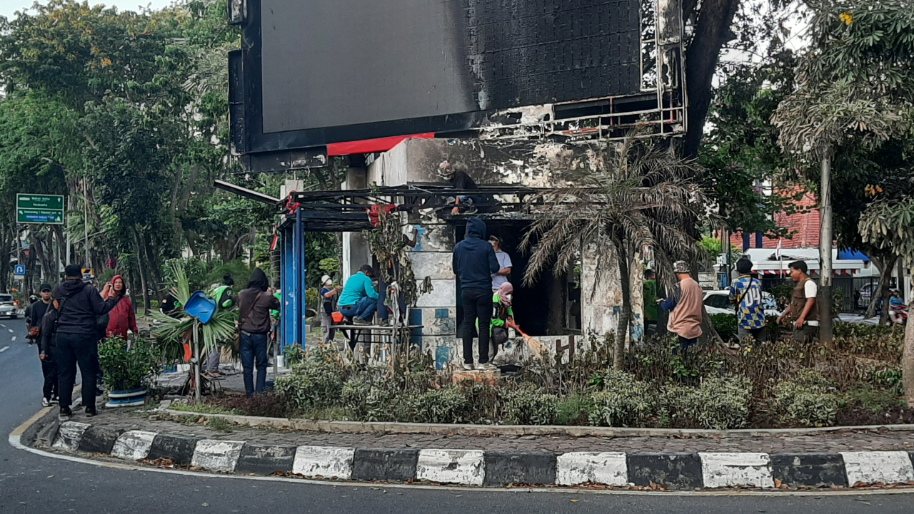 Driver ojek online bersama warga saat membersihkan puing pos polisi depan KBS pasca dibakar pendemo
