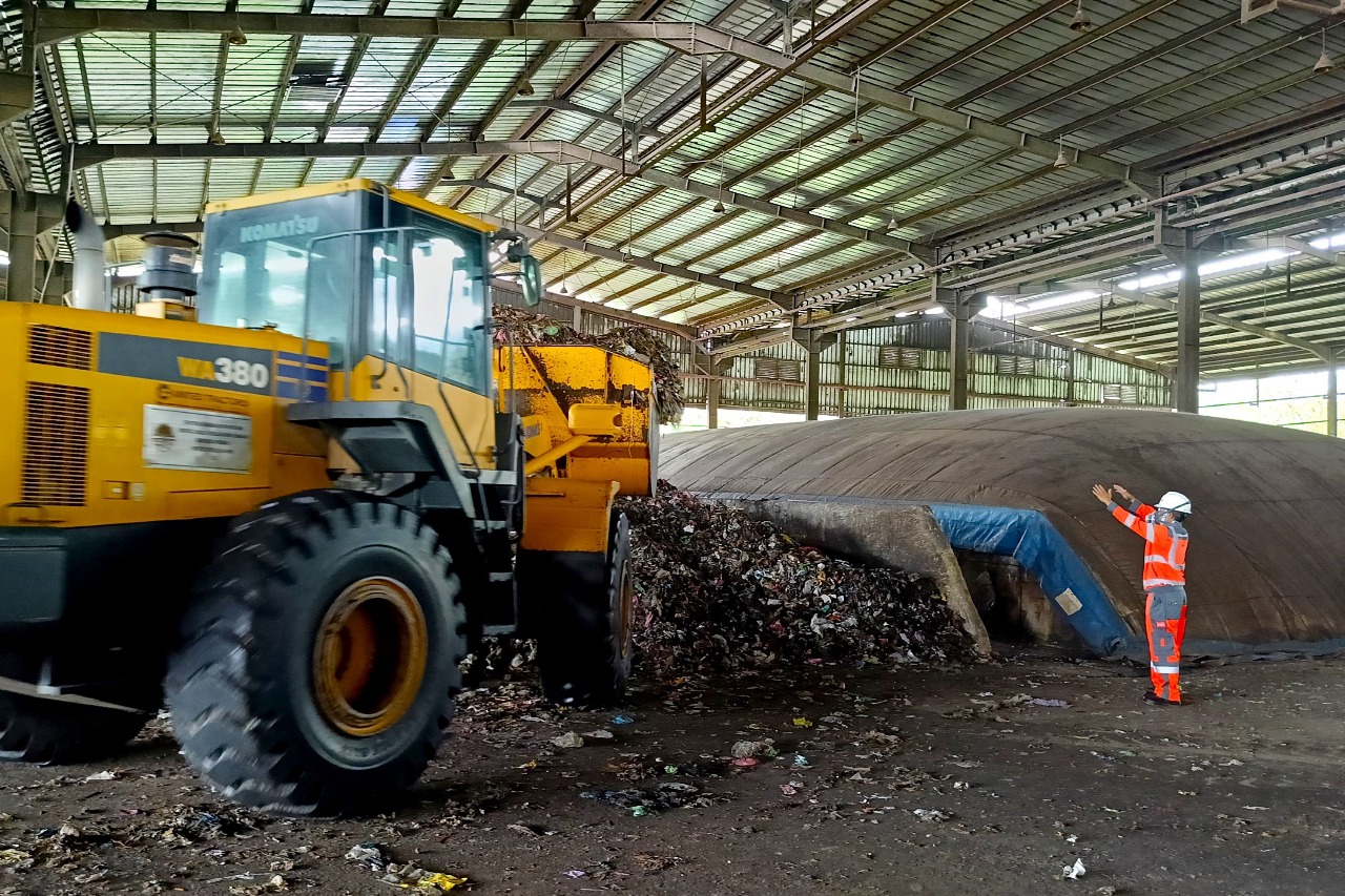 Proses pemindahan sampah basah hasil pencacahan ke tempat pengeringan yang akan diolah menjadi RDF dengan metode _biodrying_ di fasilitas pengolahan sampah menjadi bahan bakar alternatif di Kabupaten Cilacap, Jawa Tengah.