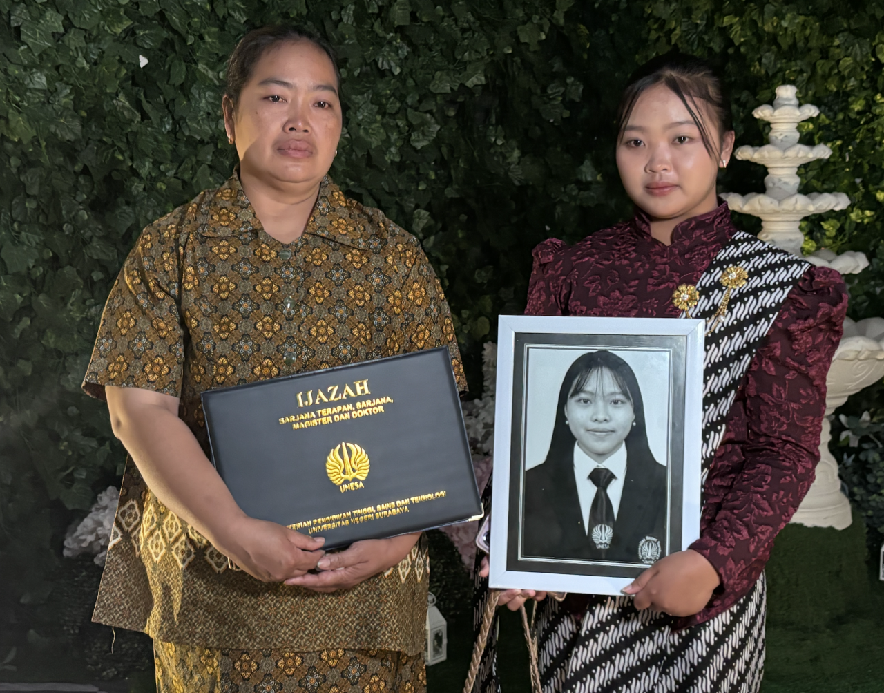 Kartiwi (kiri) bersama anaknya menunjukkan ijazah dan foto mendiang Linda Ayu Tivani usai prosesi wisuda Universitas Negeri Surabaya (Unesa), Surabaya. Linda dinyatakan lulus, namun wafat sebelum sempat mengikuti wisuda. (foto: Ardhia Tap)