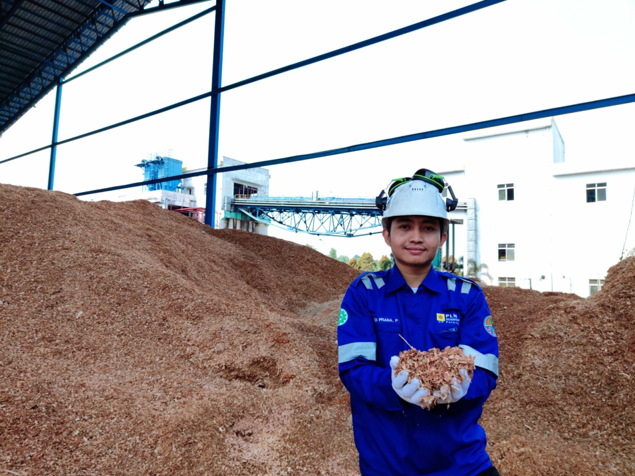 Karyawan PLN Nusantara Power menunjukan biomassa woodchip yang digunakan pada PLTU Pulang Pisau, Kalimantan Tengah. Secara total produksi energi hijau dari cofiring PLN Nusantara Power berhasil mengurangi emisi karbon dioksida hampir mencapai 600 ribu ton